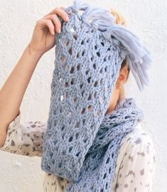 a woman wearing a blue knitted scarf with holes in the middle, covering her face