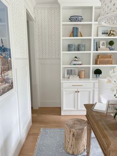 a living room with white bookcases and wooden furniture in the corner, along with a blue area rug