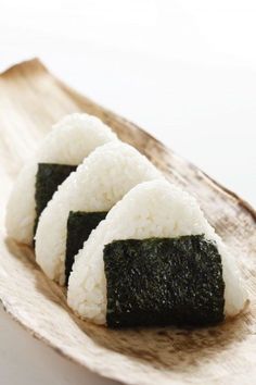 three pieces of sushi sitting on top of a wooden platter with white rice