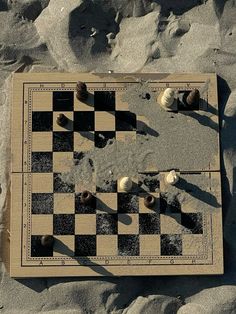 an aerial view of a chess board on the beach with shells and sand around it