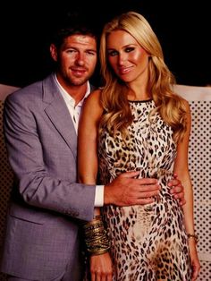 a man and woman standing next to each other in front of a wall with an animal print dress