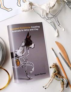 a book about creating animals in wire and clay on a table next to some crafting supplies