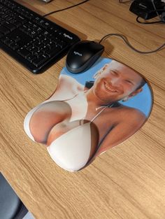 a mouse pad with an image of a naked man on it next to a keyboard