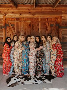 a group of women standing next to each other in long dresses and cow skin rugs