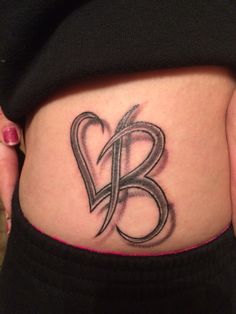 a woman's stomach with the letter b on it and an artistic tattoo design