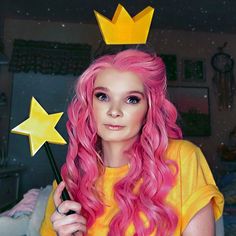 a woman with pink hair wearing a crown and holding a star wand in her hand