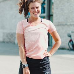 a woman standing with her hands on her hips and smiling at the camera while wearing black shorts