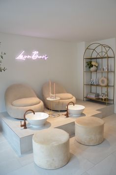 the interior of a salon with stools, tables and chairs in front of a neon sign