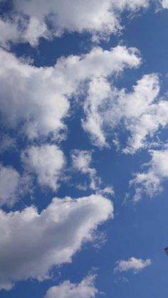 an airplane is flying in the blue sky with white clouds above it and a clock tower