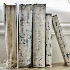 three old books sitting on top of a table next to a lamp and window sill