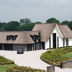 a car is parked in front of a house with a thatched roof and black shutters