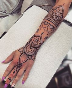 a woman's hand with a henna tattoo on her left arm and wrist