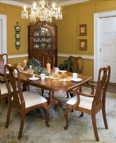 a dinning room table and chairs in front of a chandelier with candles on it