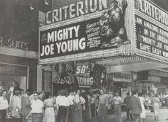 an old black and white photo of people standing in front of a movie theater sign