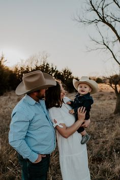 a man and woman holding a baby in a field