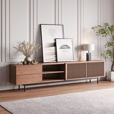 a wooden entertainment center with pictures and plants on the top, in front of a white paneled wall