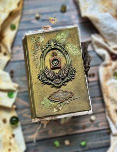 an old book sitting on top of a wooden table covered in green beads and leaves