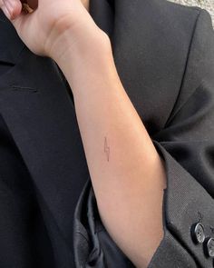 a person's arm with a small arrow tattoo on the left side of their arm