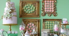 a table topped with lots of cakes and desserts next to pictures on the wall