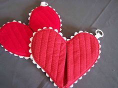 two red heart shaped cushions sitting on top of a black cloth covered table with white trim