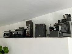 several old cameras sitting on top of a shelf