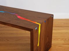 a wooden bench with multicolored lines painted on the top and bottom part of it