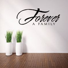 two white vases with grass in front of a wall that says forever, a family