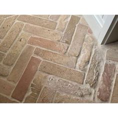 a close up view of a brick floor with an open door in the center and white trim around it