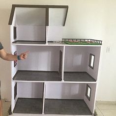 a man standing in front of a doll house made out of bookshelves and shelves