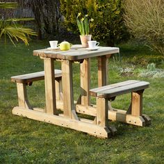 a wooden picnic table with two benches in the grass