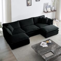 a black sectional sofa sitting on top of a white rug next to a coffee table