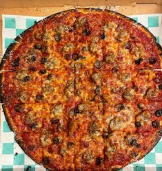 a large pizza sitting on top of a checkered table cloth