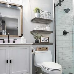 a white toilet sitting in a bathroom next to a walk in shower under a mirror