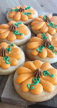 several decorated cookies sitting on top of a wooden board with green icing around them