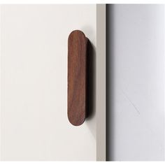 a wooden door handle on the side of a white wall