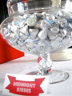 a glass bowl filled with lots of silver foiled chocolates on top of a table