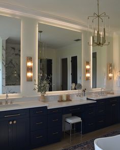 a large bathroom with double sinks and mirrors on the wall above them is illuminated by lights