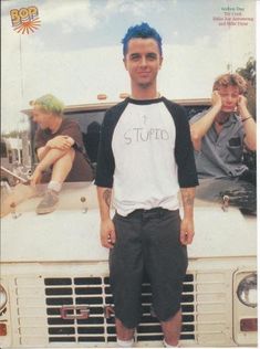 a man standing in front of a truck with his hands on his hips and two other men behind him