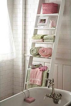 a bathroom with a ladder leaning over the bathtub and towels on the shelf above it