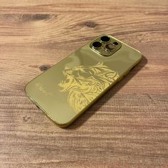 a gold phone with a golden dragon on it's back cover sitting on a wooden surface