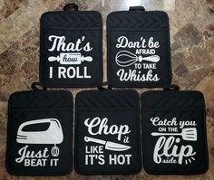 four black oven mitts with white lettering on them