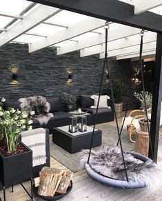 an outdoor living area with black furniture and pillows on the floor, including a swing chair