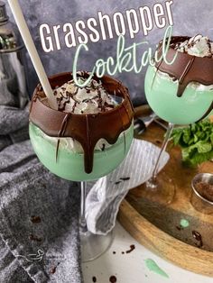 two glasses filled with ice cream and chocolate on top of a wooden table next to a sign that says grasshopper cocktail