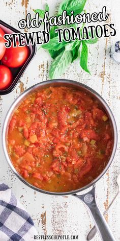 a pot filled with tomato sauce next to fresh basil leaves and tomatoes on the side