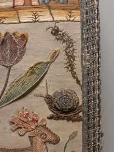 a close up of a piece of cloth with flowers and animals on it, including a snail