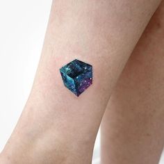 a small tattoo on the leg of a woman's arm with an image of a cube