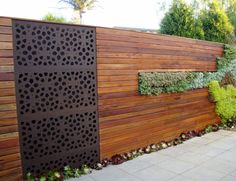 a wooden fence that has plants growing on it and in the background is a brick walkway