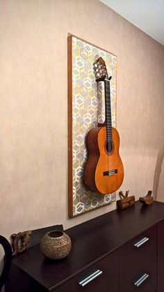 a guitar hanging on the wall next to a dresser