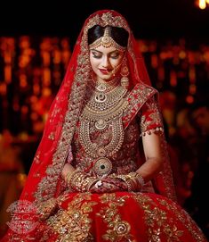 a woman in red and gold bridal gown sitting down with her hands on her hips