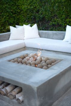 a concrete fire pit with rocks and logs around it